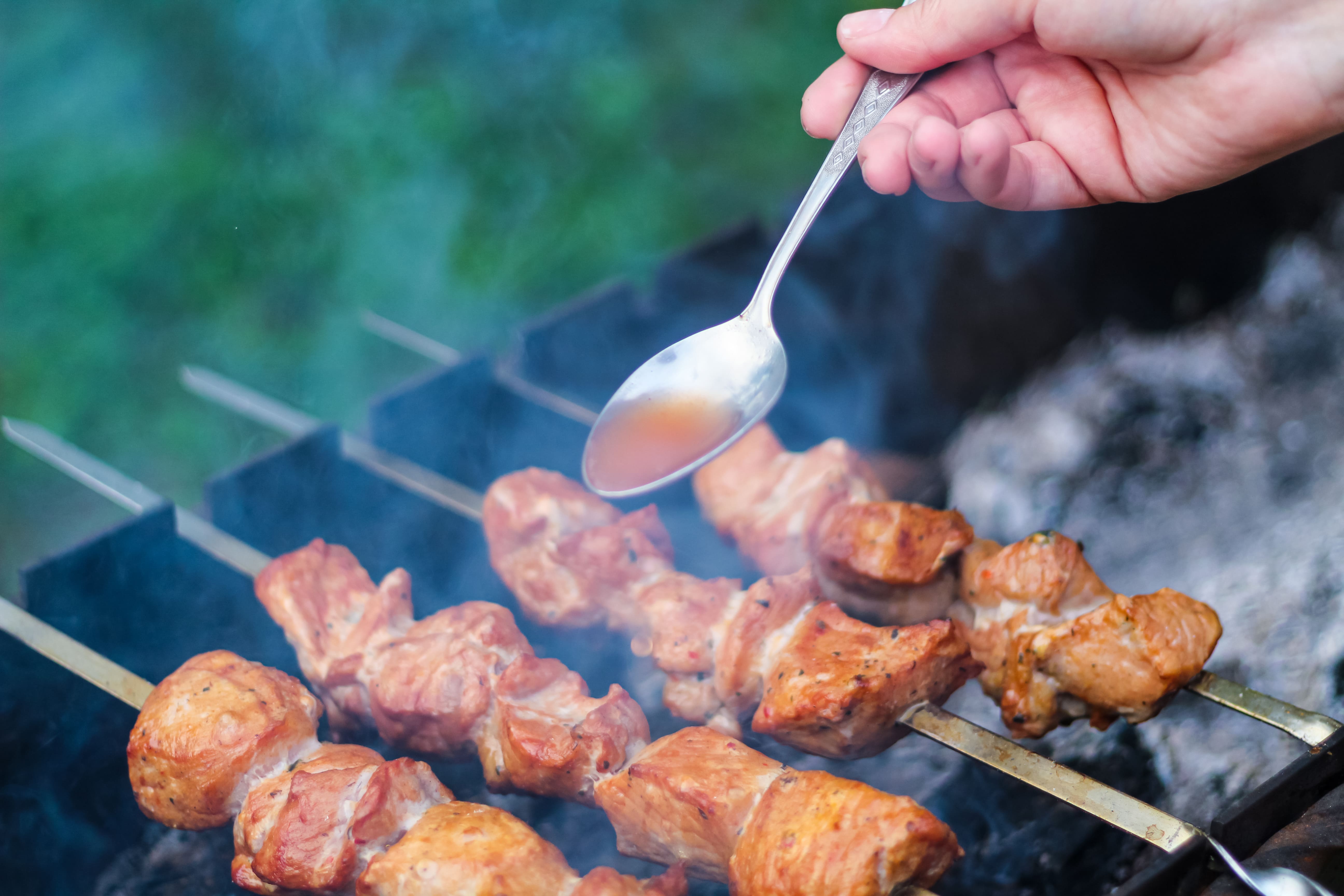 skewers-on-the-grill-with-a-spoon-pour-over-the-ma-2023-03-18-04-17-33-utc.jpg